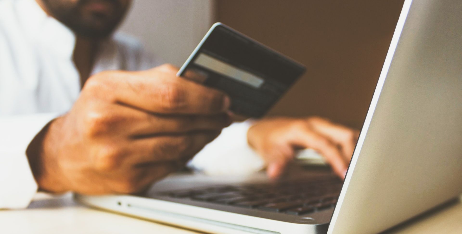 男士在打字时拿着信用卡输入信用卡详细信息